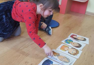 Dziewczynka dopasowuje ilustrację emocji do ilustracji twarzy.